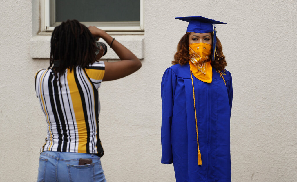 Anderson High School senior Teyaja Jones, right, poses in her cap and gown and a bandana face cover, Tuesday, May 5, 2020, in Austin, Texas. Texas' stay-at-home orders due to the COVID-19 pandemic have expired and Texas Gov..jpg