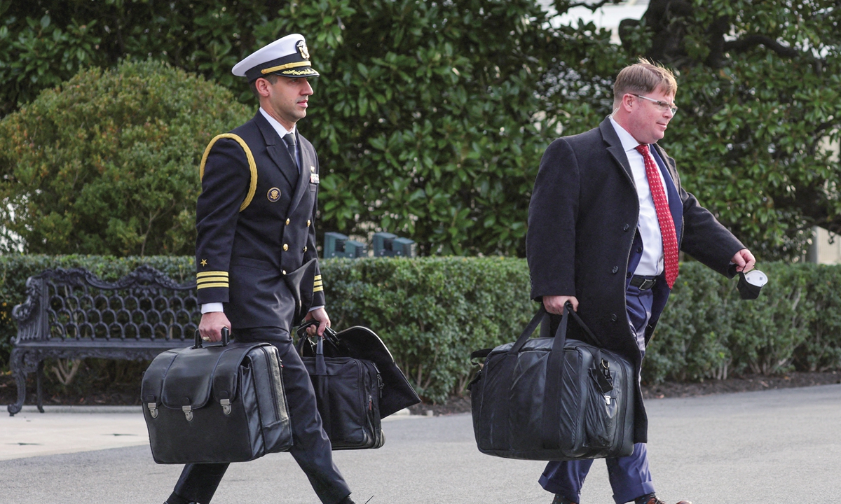 A military aide (left) carrying a briefcase, also known as the 