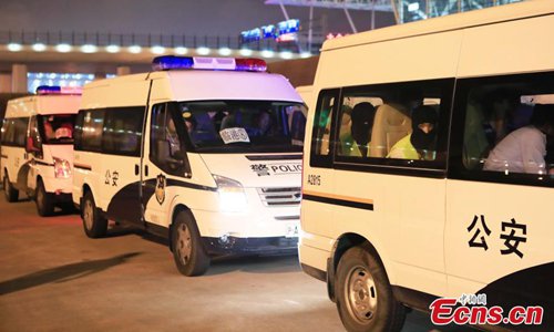 Police escort suspects caught in a social network and telecommunication fraud bust as they arrive at Pudong International Airport in Shanghai, May 14, 2019. Police detained the 57 suspects in Danzhou City of South China's Hainan Province and then transported them to Shanghai as investigations continue. (Photo: China News Service)