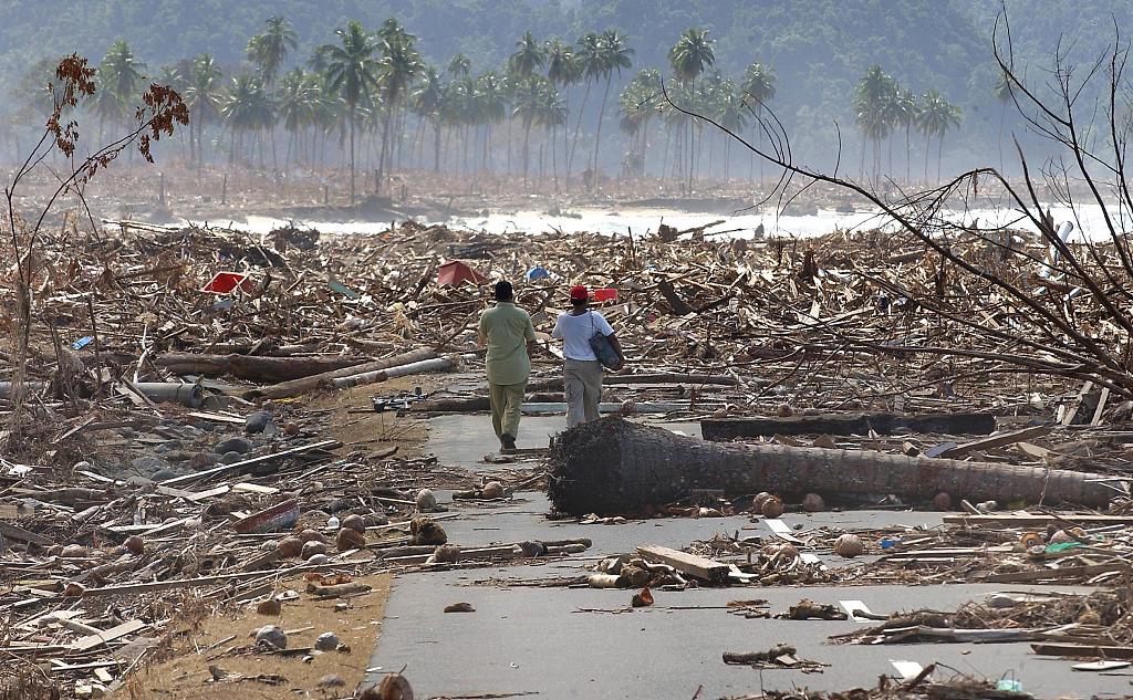 Two weeks after the Indian Ocean tsunami, two Indonesian refugees walk down a road covered with debris leftover from the tsunami disaster in the west coast town of Leupung, about 30 kms from Banda Aceh, January 09, 2005. /CFP