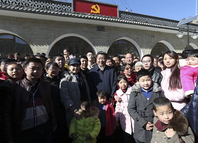 Xi Jinping and Peng Liyuan take photos with local residents in Liangjiahe Village, Shaanxi Province, on February 13, 2015. [File Photo: Xinhua]
