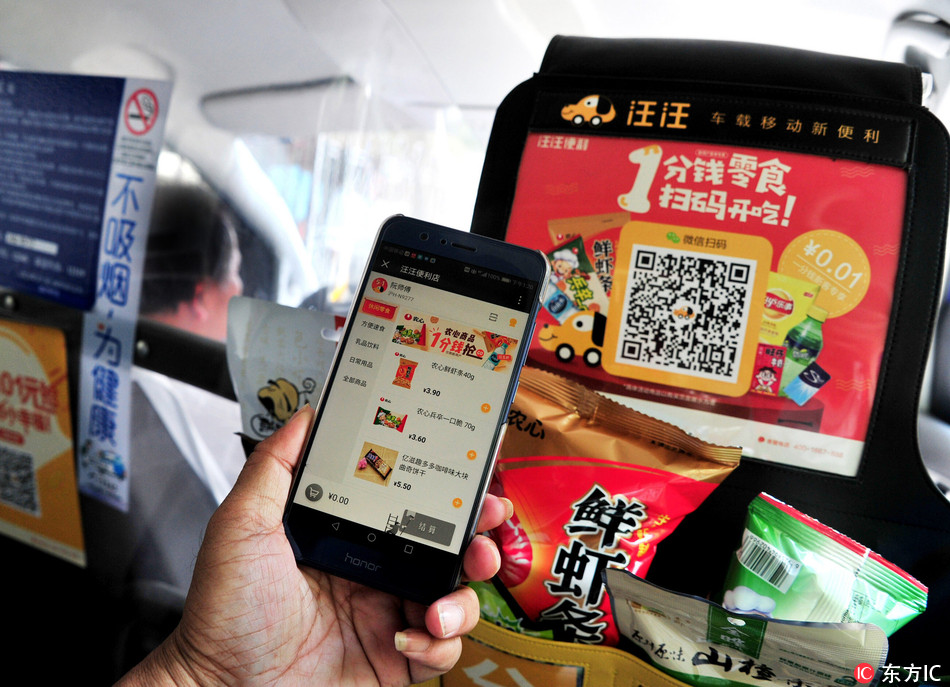 A passenger uses an app on his smartphone to buy snacks and drinks in a taxi in Shanghai, on Tuesday, May 15, 2018. [Photo: IC]