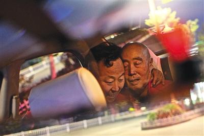 45-year-old taxi driver Li Jinzhu (Left) hugs his father inside his vehicle. [File Photo: The Beijing News]