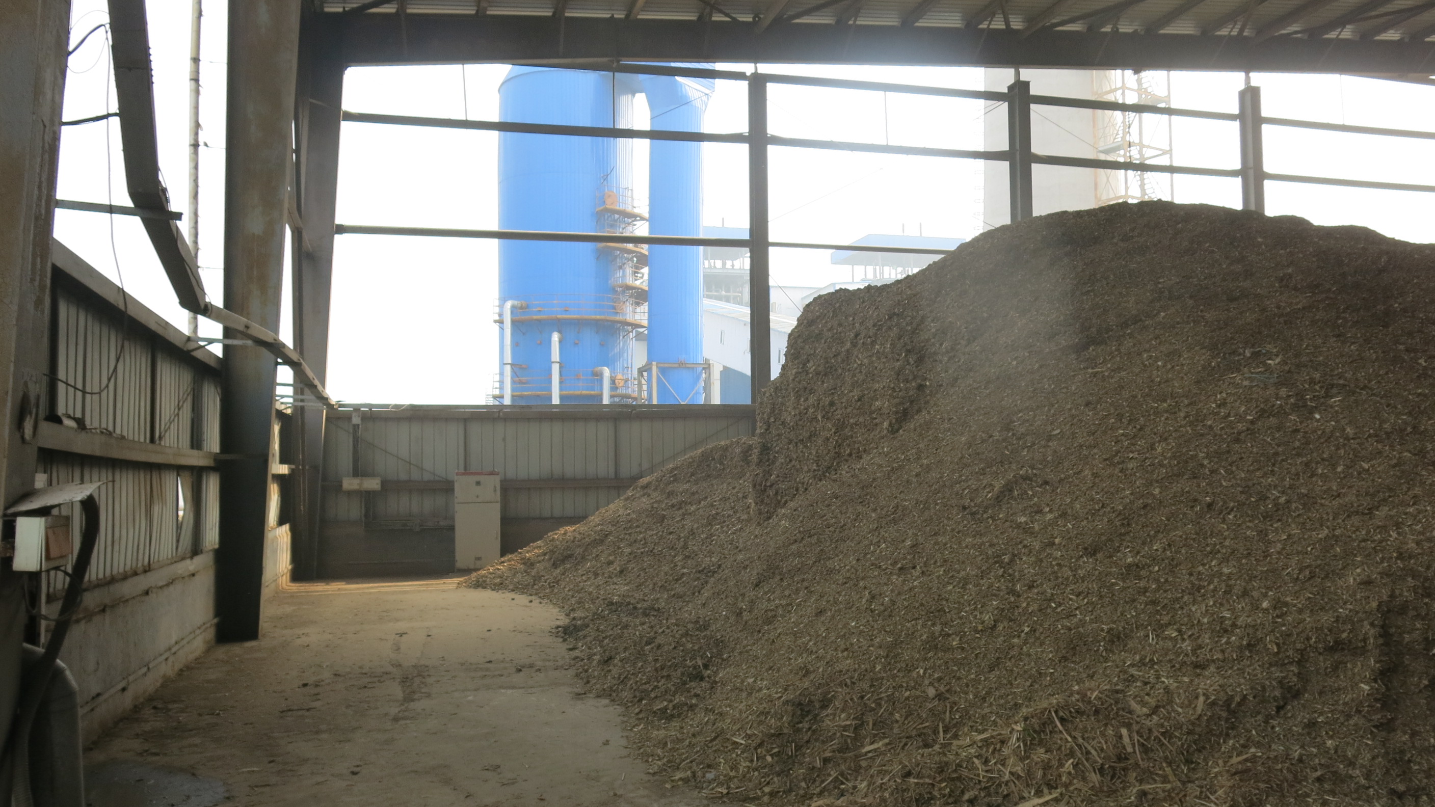 Tons of bio-waste to be transformed into energy in the turbo-generator in the background, at the Shanxi Xinshitai Green Energy power plant. [Photo by Chris Georgiou / China.org.cn]
