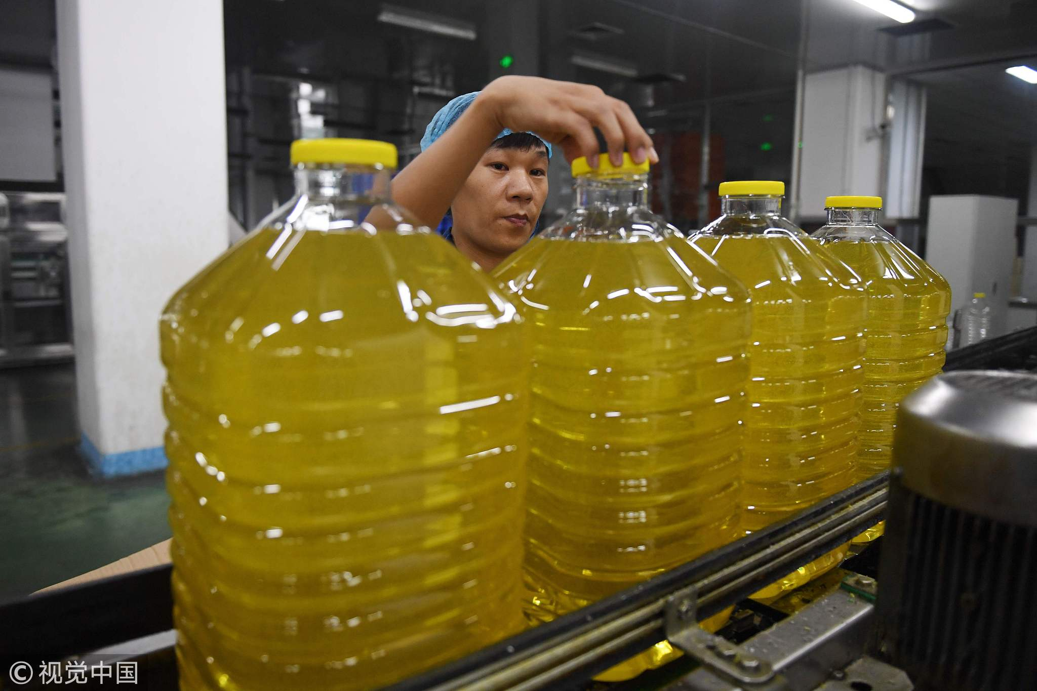 A worker checking a cap on a bottle of soybean oil at the Hopeful Grain and Oil Group factory in Sanhe, in China's northern Hebei province. The company uses soybeans imported from Brazil, after recently changing from a US supplier, July 19, 2018. [Photo: VCG] 