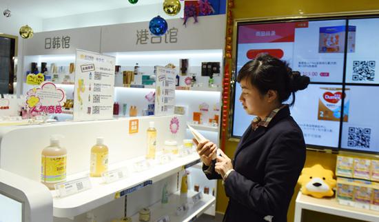 A customer selects imported items at a cross-border e-commerce experience store in Hangzhou. (Photo by Long Wei / for China Daily)