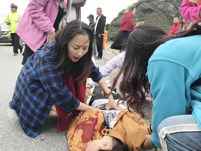 Zhou Wei helps to treat a person injured in the accident. [Photo: thepaper.cn]