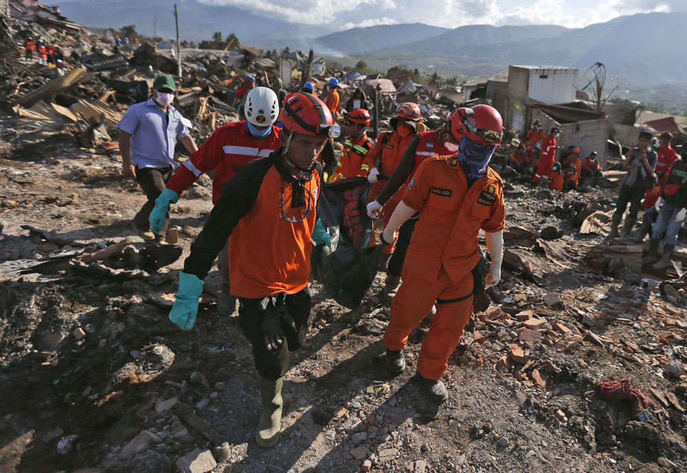 Rescuers remove the body of an earthquake victim from the devastated village of Balaroa in Palu, Central Sulawesi, Indonesia, Monday, Oct. 8, 2018. [Photo: AP/Dita Alangkara]