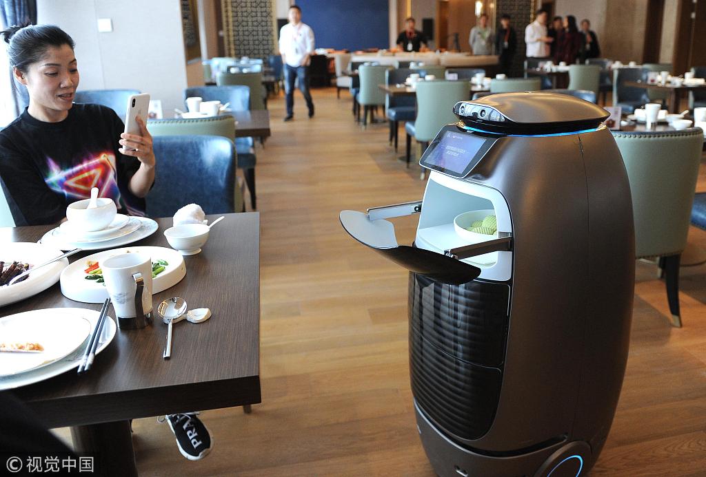 A guest takes a picture of a food delivery robot in the restaurant at Alibaba's AI-driven "Flyzoo Hotel" in Hangzhou, Zhejiang Province, December 17, 2018. [Photo: VCG]