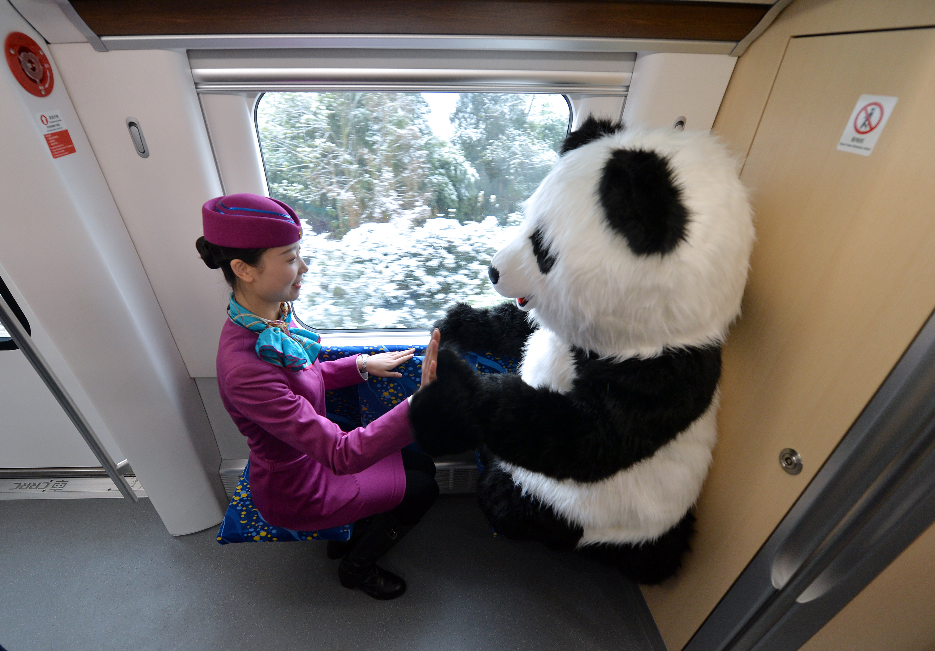 A train attendant "high fives" the train's panda mascot on Tuesday, December 29, 2018. [Photo: IC]