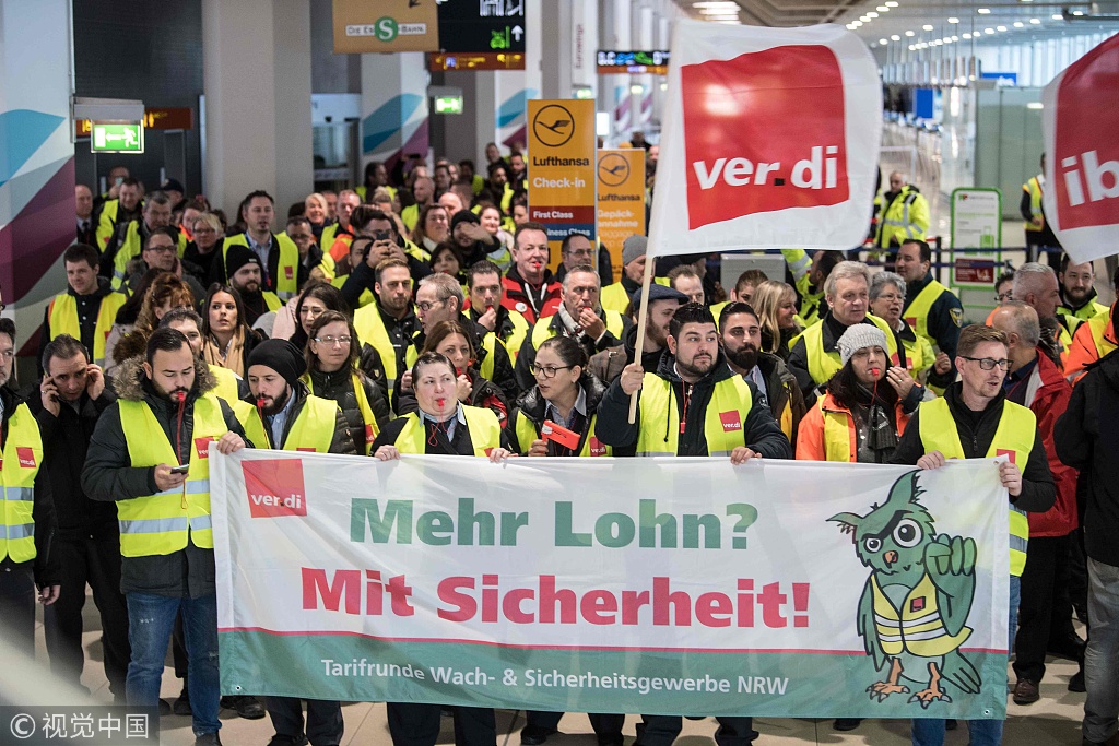 Members of Germany's Verdi union hold a banner reading "more pay? With security (certainty)" at a terminal during a one-day strike by security staff at Cologne's airport on January 10, 2019. [Photo: VCG]