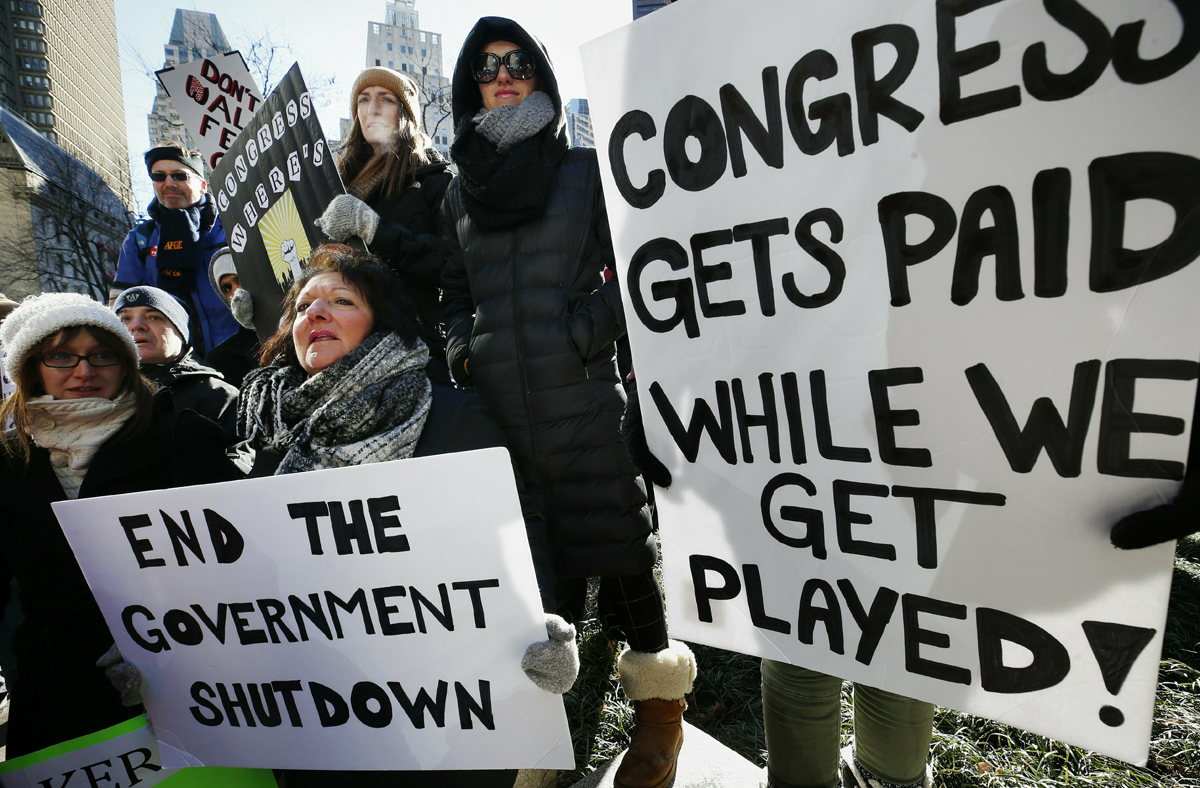 Government workers and their supporters hold signs during a protest in Boston, Friday, Jan.11, 2019. The workers rallied with Democratic U.S. Sen. Ed Markey and other supporters to urge that the Republican president put an end to the shutdown so they can get back to work. [Photo: AP/Michael Dwyer]