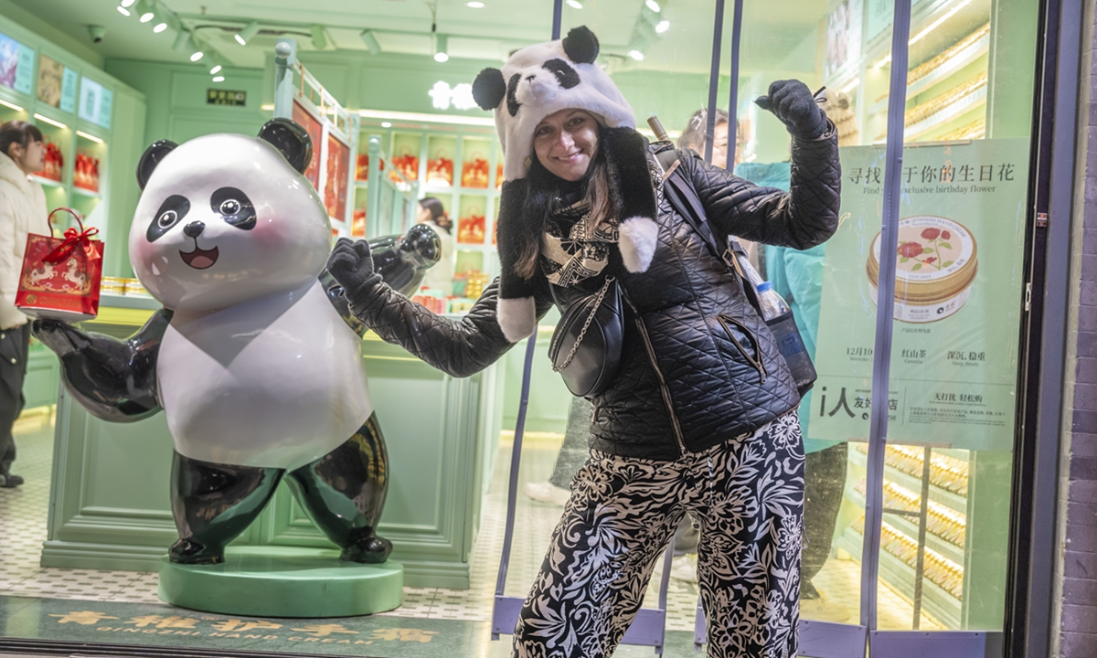 A foreign tourist takes photos with a panda model while visiting <span><span class=