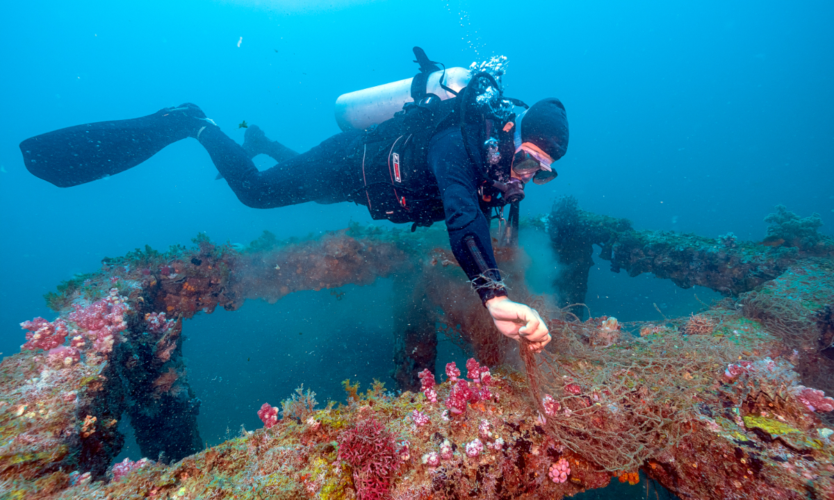 A staff member from the marine department on Wuzhizhou Island in Sanya, South China’s Hainan Province, clears fishing nets. Photo: Cao Wenxuan/People’s Daily