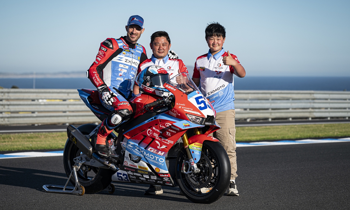 Zhang Xue (center) poses for a photo with his son (right) and motobike racing driver Valentin Debise. Photos: Courtesy of the Evan Bros team