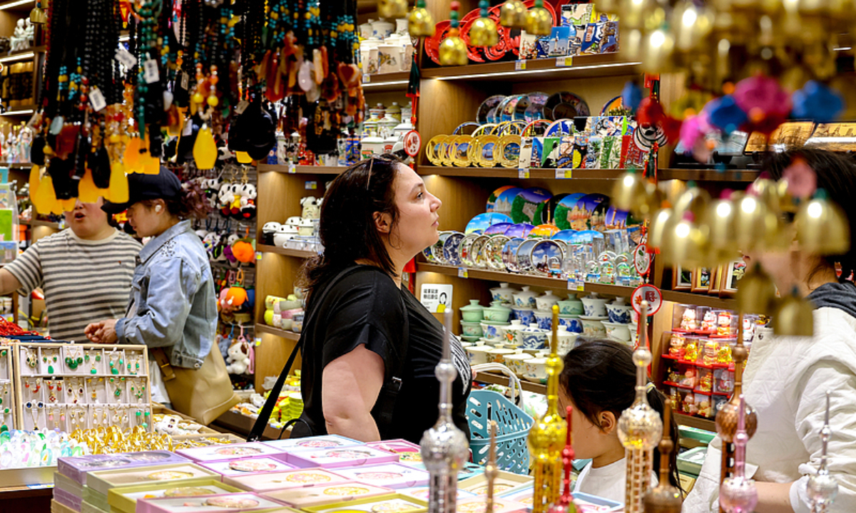 A foreign visitor buys souvenirs at Yuyuan Garden in Shanghai during the May Day holidays. Photo: VCG