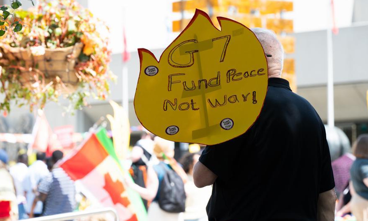 A protester holds a sign during a rally in Calgary, Canada, June 15, 2025. Photo: Xinhua