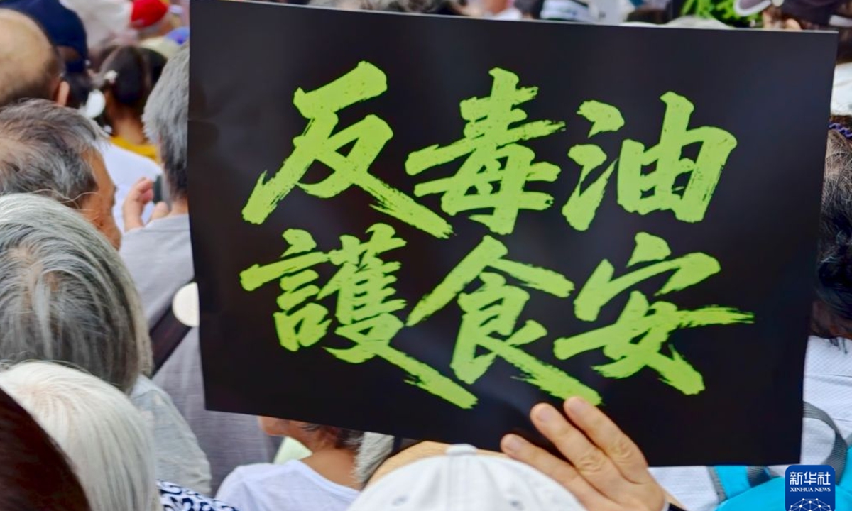 A Taiwan resident holds up a placard reading oppose toxic oil, protect food safety during a protest on July 25. Photo: Xinhua