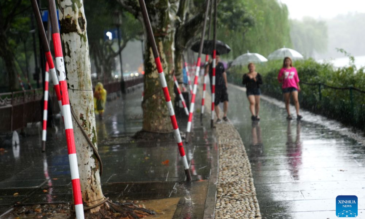 Visitors walk past temporarily reinforced trees along the West Lake in Hangzhou, east China's Zhejiang Province, Aug. 9, 2026. China's national observatory on Sunday activated a red alert -- the highest level in the country's typhoon warning system -- as Typhoon Dolphin approaches.Typhoon Dolphin is forecast to make landfall along the country's east coast from Zhoushan in Zhejiang Province to Fuding in Fujian Province, according to the National Meteorological Center (NMC). (Xinhua/Han Chuanhao)