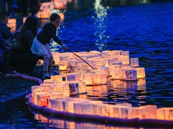 People release illuminated lanterns onto water during Water Lantern Festival in Coquitlam, Canada
