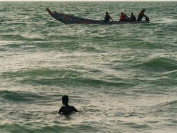 People enjoy leisure time amid traditional wooden pirogues at Nouakchott Fishing Port in Mauritania
