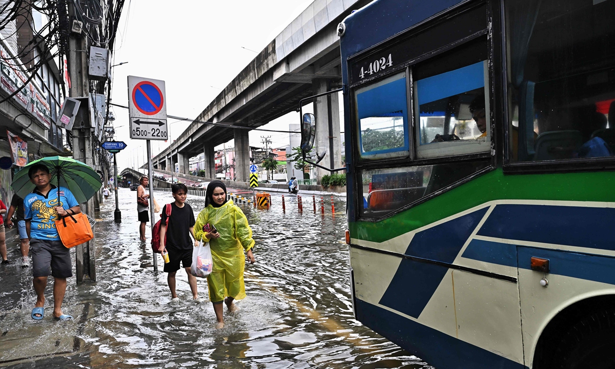 People hail a public bus on a flooded road in Ramkhamhaeng district in Bangkok on September 27, 2026, after downpours have been sweeping through many areas in Thailand in recent days. Photo: VCG