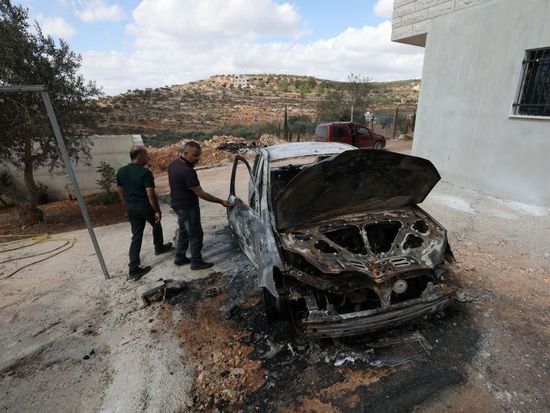 Palestinians inspect vehicles burnt by Israeli settlers in West Bank