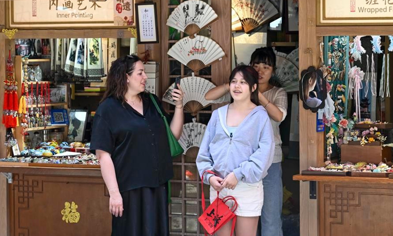 A foreign tourist tries on hair ornaments at a mall in Shanghai, east China, May 5, 2026. (Xinhua/Chen Haoming)