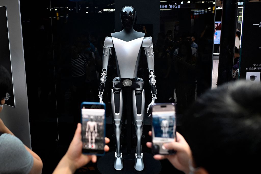 Visitors take photos of a Tesla robot displayed at the World Artificial Intelligence Conference (WAIC) in Shanghai, July 6, 2023. /CFP