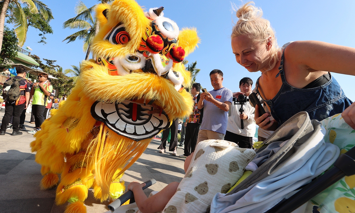 Foreign tourists interact with performers during a lion dance performance at a scenic spot in Sanya, South China's Hainan Province, on January 17, 2026. Photo: VCG