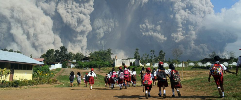 School children walk as Mount Sinabung erupts in Karo, North Sumatra, Indonesia, Monday, Feb. 19, 2018. Rumbling Mount Sinabung on the Indonesian island of Sumatra has shot billowing columns of ash more than 5,000 meters (16,400 feet) into the atmosp