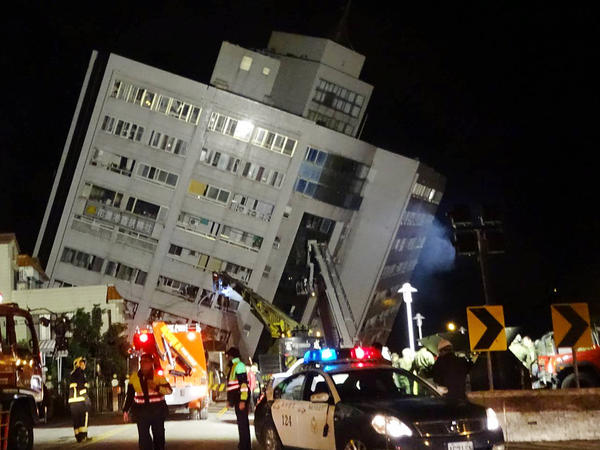 Rescuers are seen entering a building that collapsed onto its side from an early morning 6.4 magnitude earthquake in Hualien County, eastern Taiwan, Wednesday, Feb. 7 2018.