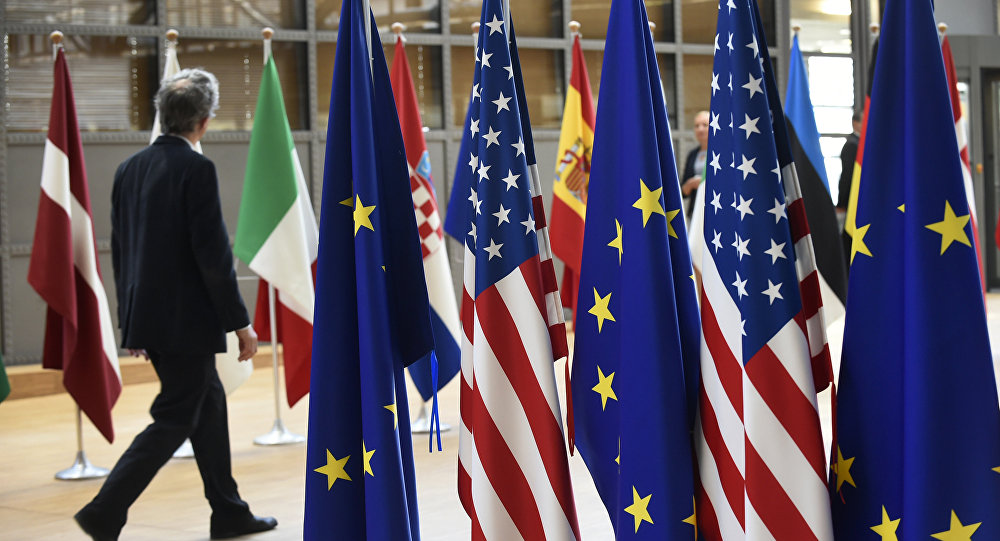 A man walks near US and European Union flags at the EU headquarters on May 15, 2017 in Brussels