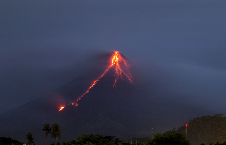 Lava continues to cascade down the slopes of Mayon volcano as seen from Legazpi city, Albay province, around 340 kilometers (210 miles) southeast of Manila, Philippines, at dawn Tuesday, Jan. 16, 2018. Glowing red lava was rolling down the slopes of a Philippine volcano as authorities maintain a warning of a possible hazardous eruption. (AP Photo/Earl Recamunda)