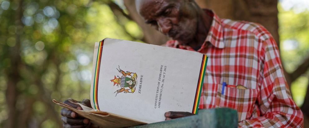 An unemployed man reads up on Zimbabwean constitutional law to understand the process of possible presidential impeachment, in a park opposite the parliament building in downtown Harare, Zimbabwe Tuesday, Nov. 21, 2017. Zimbabwean President Robert Mu
