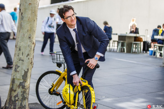 A man locks an ofo shared-bike after he finishes riding in Sydney, Australia, on September 25, 2017. [Photo: IC]