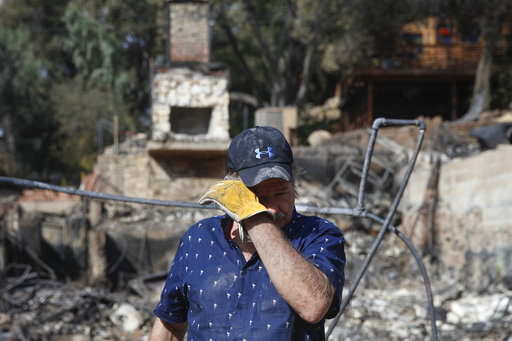 Roger Kelton, 67, wipes his tears while searching through the remains of his mother-in-law's home burned down by the Woolsey Fire Tuesday, Nov. 13, 2018, in Agoura Hills, Calif. [Photo: AP]