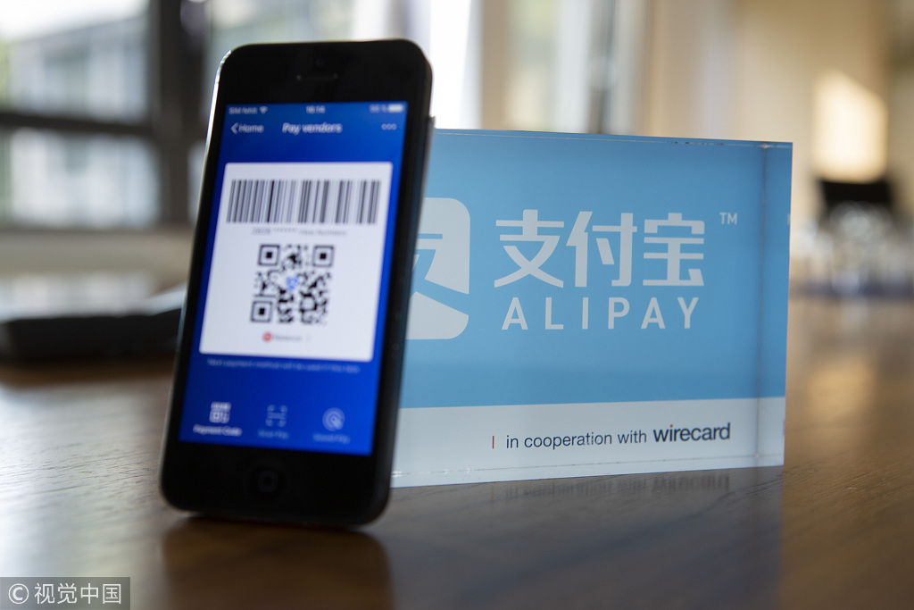 An Alipay digital payment app logo and smartphone sit on a desktop. [Photo: VCG]