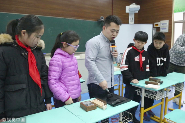 A craftsman specializing in Chinese characters demonstrates how to make a movable type printing at the West Lake Primary School in Hangzhou on Tuesday, March 5, 2019. [Photo: VCG]