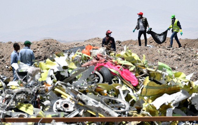 A crew working with an investigative team to clear the site after the crash of the Ethiopian Airlines operated Boeing 737 MAX aircraft, carry debris at Hama Quntushele village in the Oromia region, on March 13, 2019. [Photo: AFP]