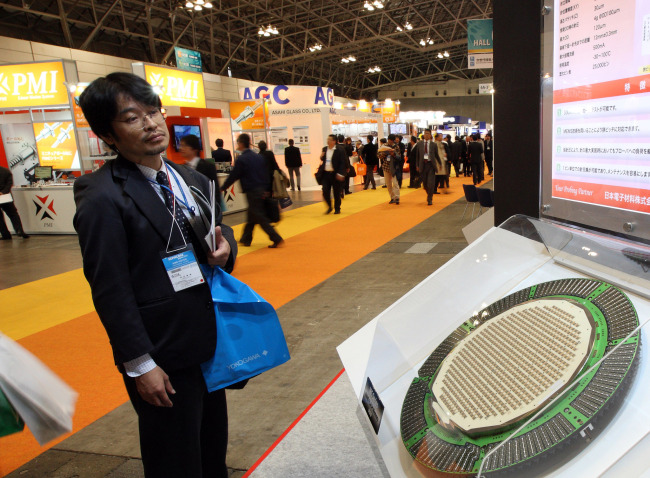 A visitor looks at a silicon wafer displayed at SEMICON Japan 2010 in Chiba, Japan, on Wednesday, Dec. 1, 2010. [File Photo: VCG]